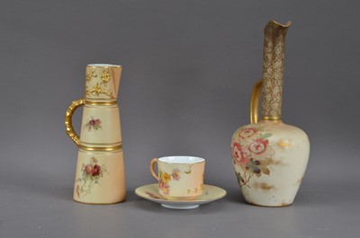Lot 149 - Three pieces of Royal Worcester ivory porcelain, comprising a slender handled jug, with heightened gilt decoration, 20.5cm high, together with a cup and saucer, all with printed marks to the underside