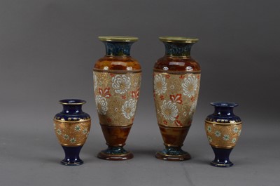 Lot 238 - A pair of Doulton Lambeth salt-glazed stoneware vases, brown with floral decoration and heightened gilt, 29cm high, together with a pair of Royal Doulton smaller vases, blue, with floral decoration