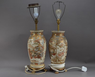 Lot 347 - A pair of Japanese ceramic satsuma style vases converted to lamps, both with panels depicting warriors, both cracked and damaged, raised on gilt metal paw feet, both approx. 55cm high AF, both require