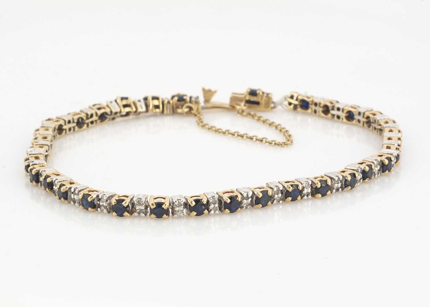 Lot 64 - A 9ct gold two colour sapphire and diamond tennis bracelet