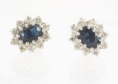 Lot 83 - A pair of oval sapphire and diamond cluster stud earrings