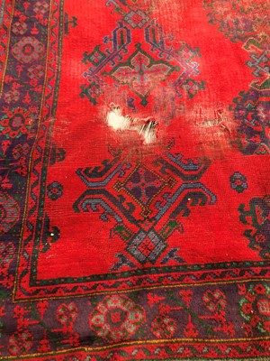 Lot 29 - A large and damaged colourful oushak woollen rug