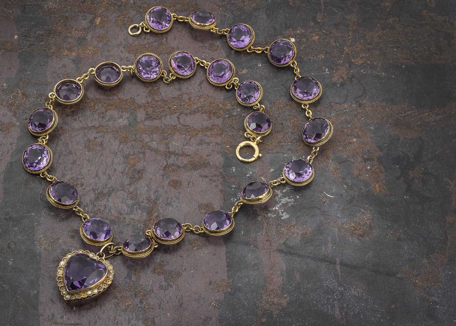 Lot 30 - An Edwardian amethyst and seed pearl heart shaped pendant and chain