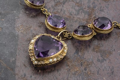 Lot 30 - An Edwardian amethyst and seed pearl heart shaped pendant and chain