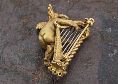 Lot 36 - A Continental 18ct gold brooch or pendant depicting Cupid playing harp