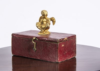 Lot 689 - An early 19th century small red leather box surmounted with a gilt metal cherub