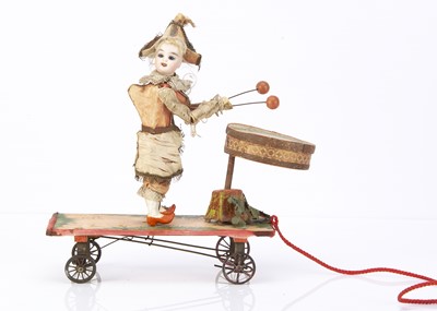 Lot 1013 - A late 19th century bisques headed drumming Punchinello pull along toy