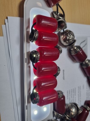 Lot 176 - A string of Middle Eastern simulated cherry amber and white metal beads