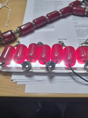 Lot 176 - A string of Middle Eastern simulated cherry amber and white metal beads