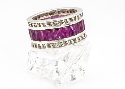 Lot 204 - A modern silver CZ and synthetic ruby eternity ring, the thick band with central pave set panel of red stones, flanked by a bands pf CZs, ring size O, marked 925, 10g