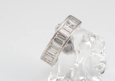 Lot 209 - A continental white gold diamond baguette channel set three-quarter eternity ring