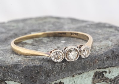Lot 129 - A three stone 18ct gold and platinum diamond dress ring
