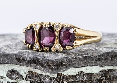 Lot 100 - An 18ct gold three stone garnet and diamond dress ring