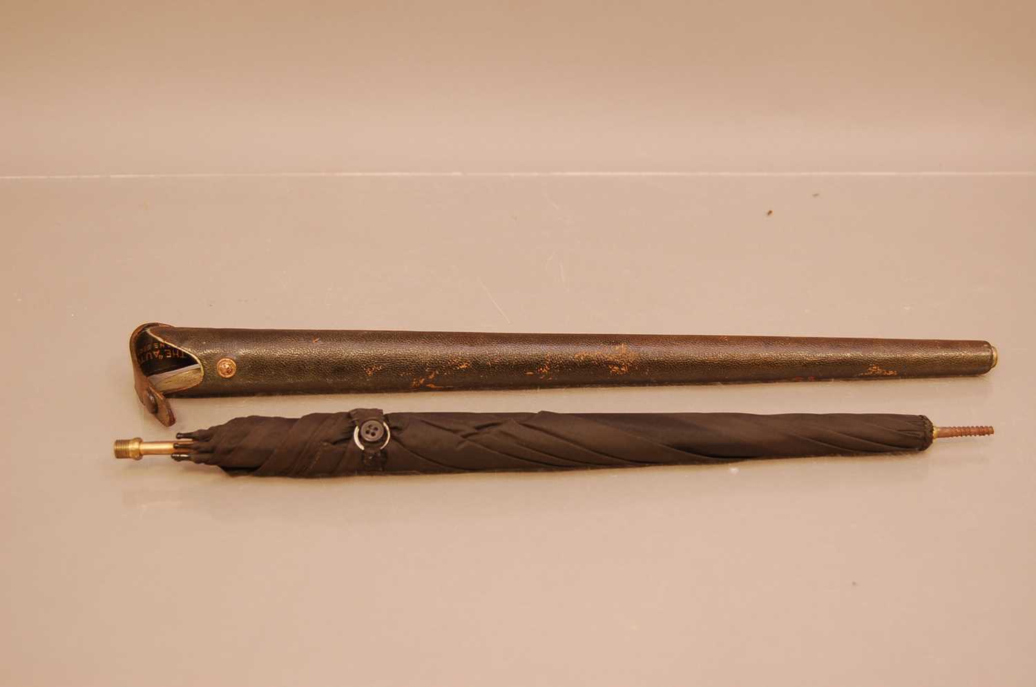 Lot 129 - An early 20th century umbrella, titled The Auto to inner of case, the leather case housing the black umbrella that screws into the case handle, lacks finial