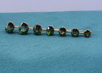 Lot 117 - A green zircon graduated bar brooch