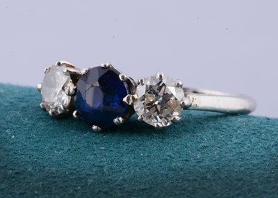 Lot 129 - A white metal three stone sapphire and diamond dress ring