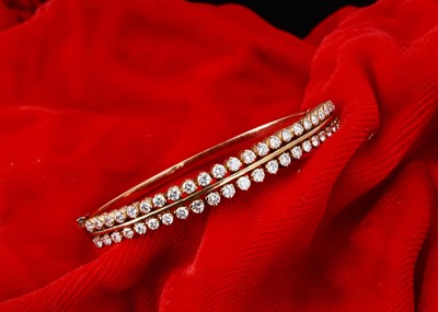 Lot 201 - A continental yellow metal and double row diamond hinged bangle