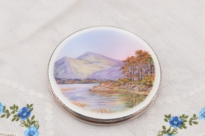 Lot 273 - A circular silver, enamelled and painted compact depicting Derwent Water