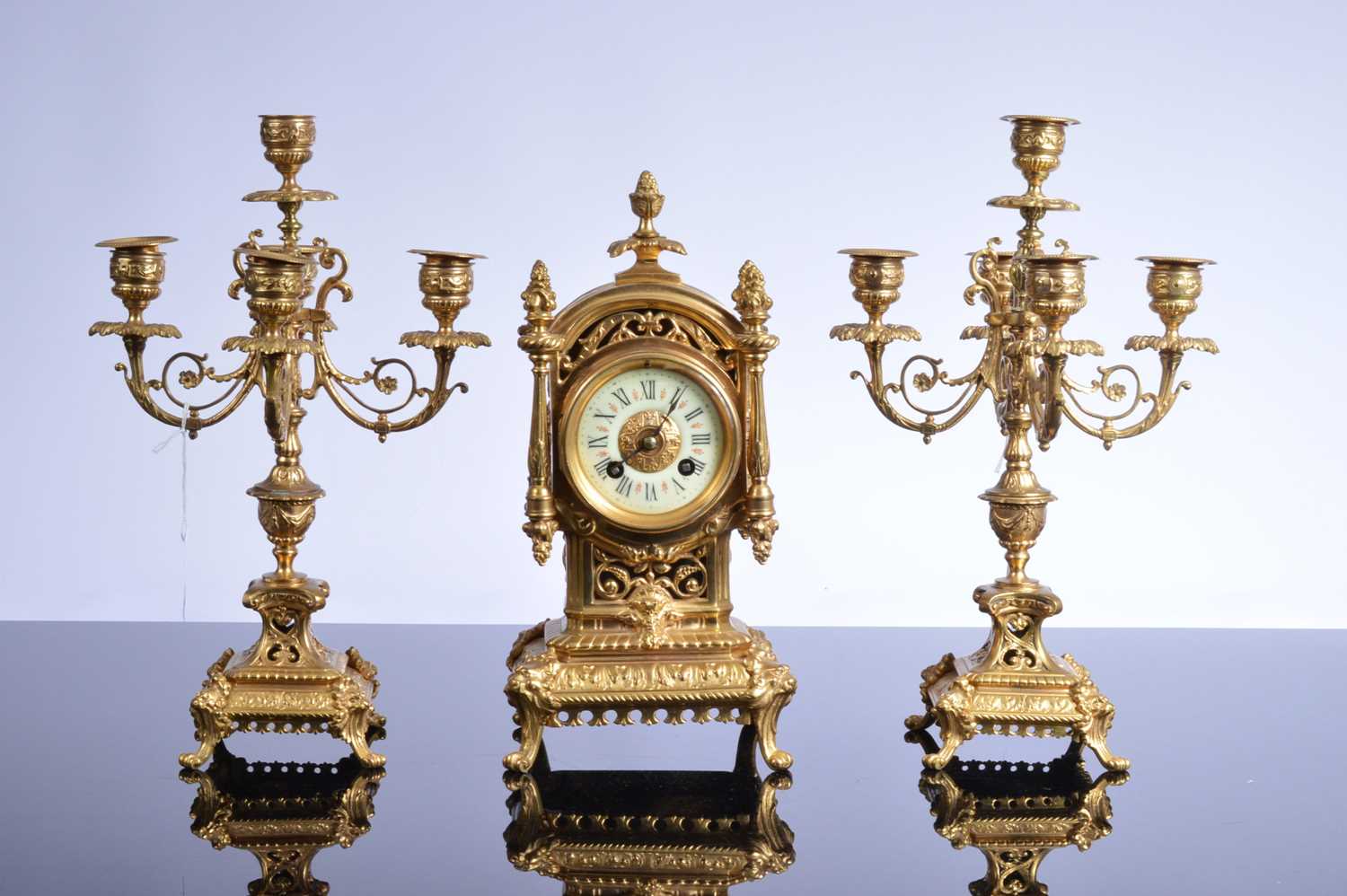 Lot 21 - A late 19th or early 20th century brass mantle clock garniture