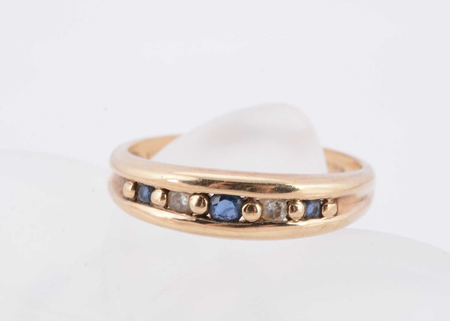 Lot 63 - A channel set sapphire and diamond half hoop 9ct gold dress ring