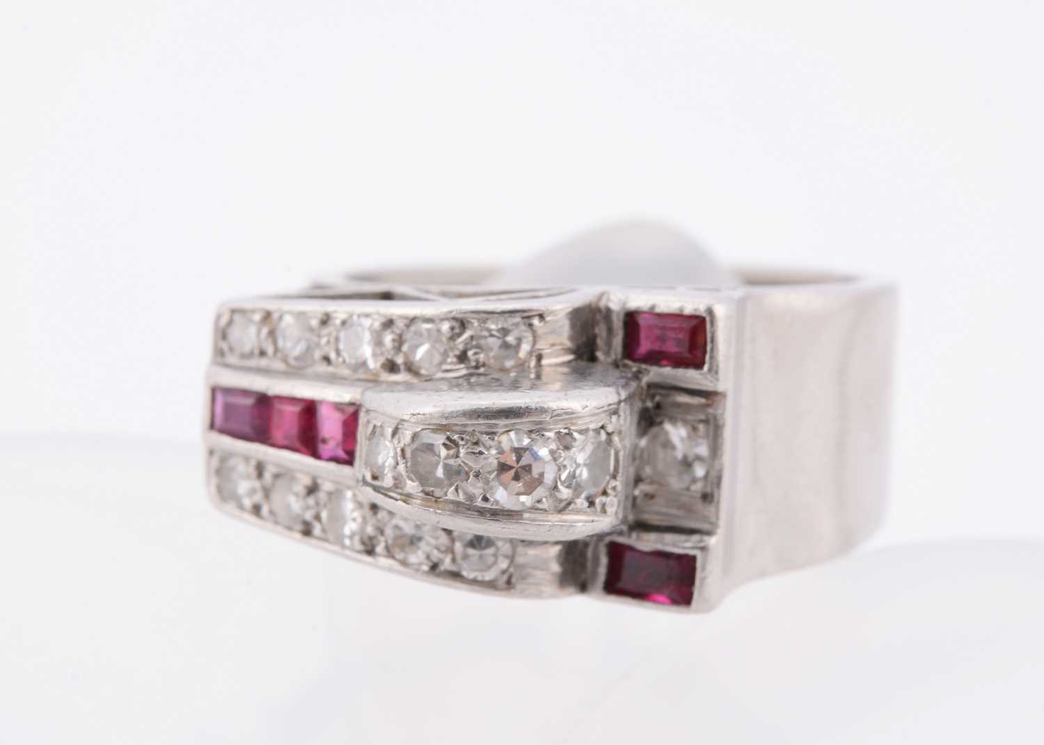 Lot 141 - An art deco ruby and diamond stylised buckle ring