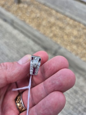 Lot 141 - An art deco ruby and diamond stylised buckle ring
