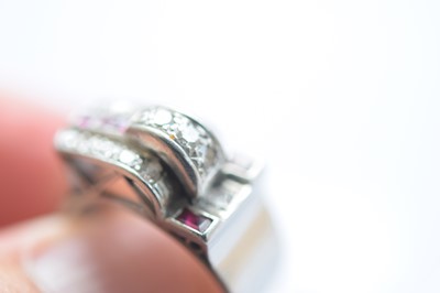 Lot 141 - An art deco ruby and diamond stylised buckle ring