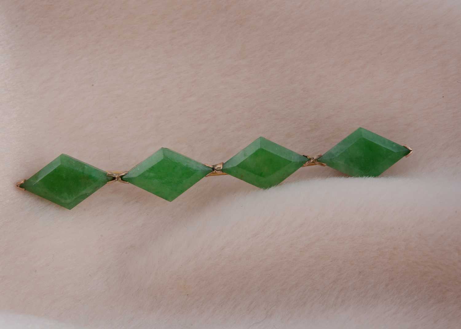 Lot 79 - A yellow metal and jadeite jade bar brooch of four lozenge shaped cut panels