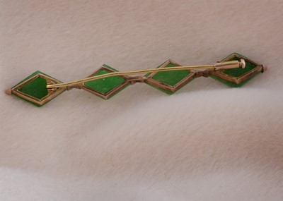 Lot 79 - A yellow metal and jadeite jade bar brooch of four lozenge shaped cut panels