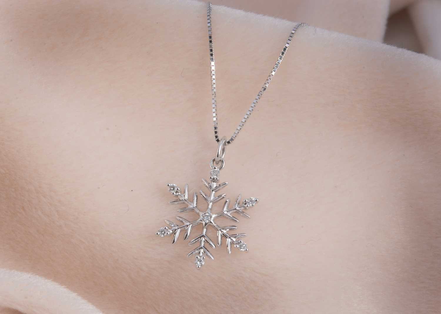 Lot 114 - A 9ct gold diamond set snowflake designed pendant