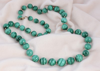 Lot 225 - A graduated string malachite spherical beads united by a gold clasp with yellow metal spacers