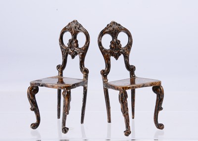 Lot 629 - Two 19th century German cast-metal and tinplate dolls’ house chairs