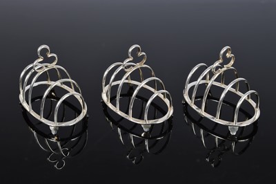 Lot 348 - A set of three George V silver small toast racks by Deakin & Francis