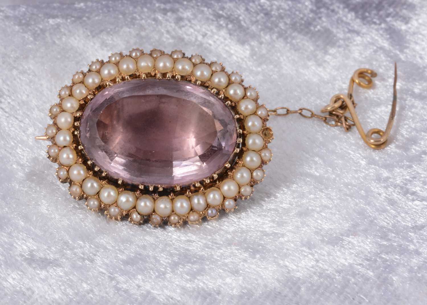 Lot 84 - An oval amethyst and seed pearl foil backed brooch