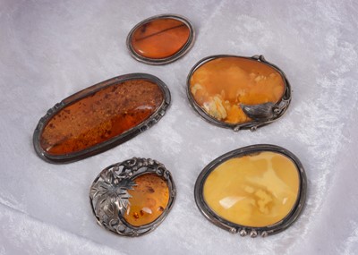 Lot 139 - Four large amber and silver set pebble brooches
