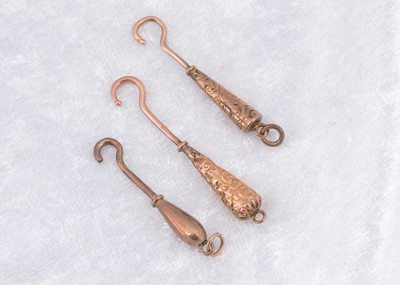 Lot 267 - Three miniature yellow metal and steel button hooks