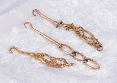 Lot 283 - Three ornate yellow and gilt metal button hooks