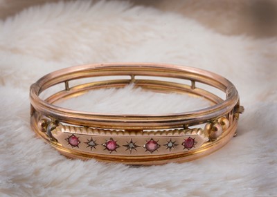 Lot 36 - A 9ct gold diamond and red paste hinged bangle